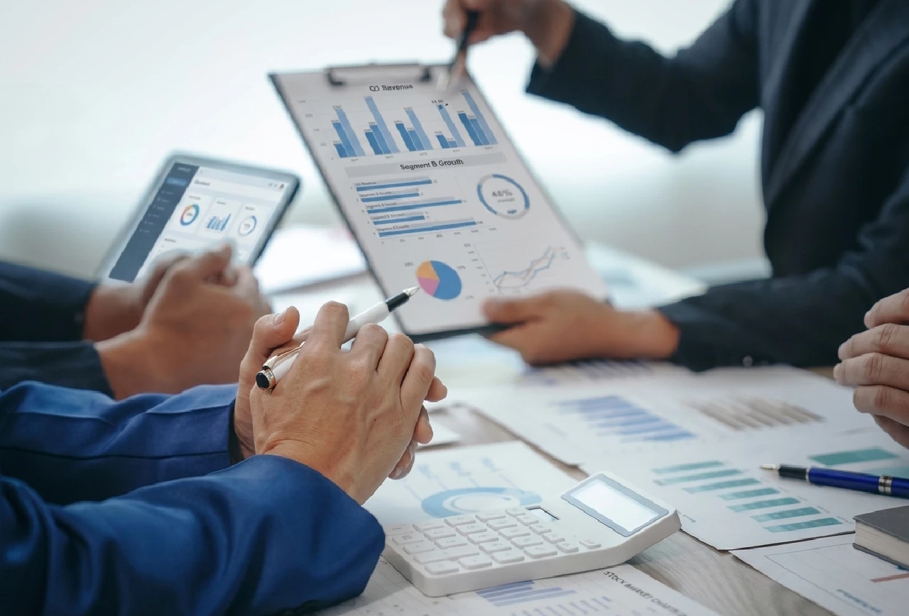 Equipo multidisciplinario de outsourcing contable analizando reportes financieros gerenciales y gráficos de rendimiento junto a sus clientes en una mesa de trabajo.
